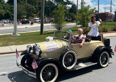 Ample Ambassador waving from a vintage antique car
