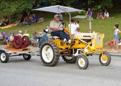 Man driving an old yellow tractor in the King Apple parade in Hendersonville, NC